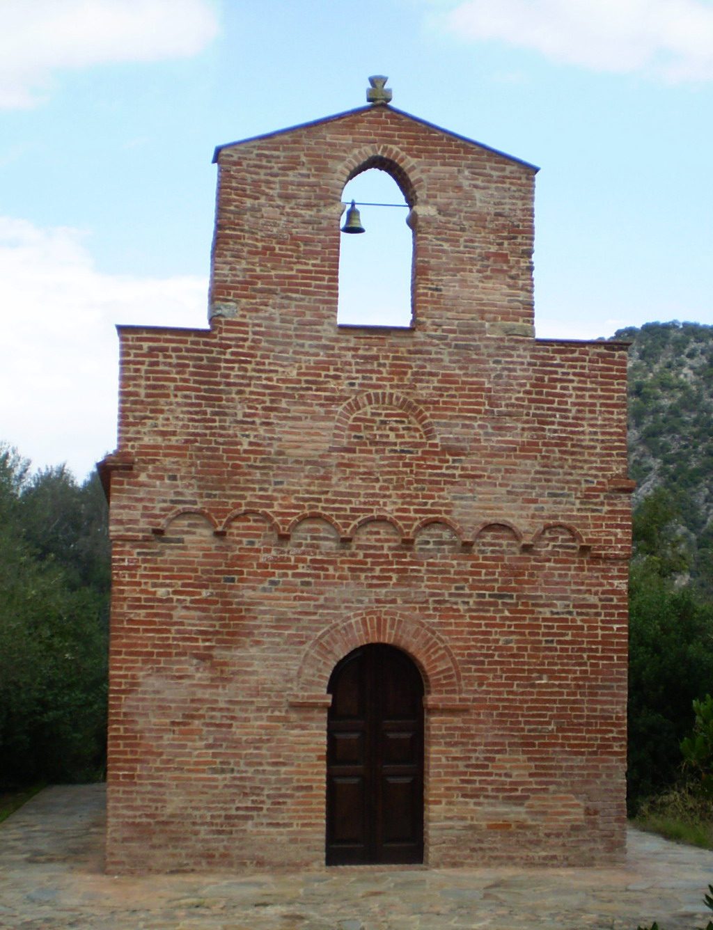 Facciata in mattoni rossi della chiesa romanica di San Nicola di Quirra con campanile a vela