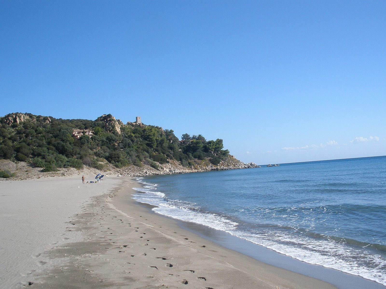 Spiaggia di Colostrai a Muravera con sabbia chiara, mare blu e promontorio coperto di macchia